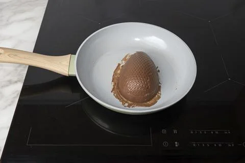 Half of a milk chocolate Easter egg with hazelnut cream filling on a frying p Stock Photos