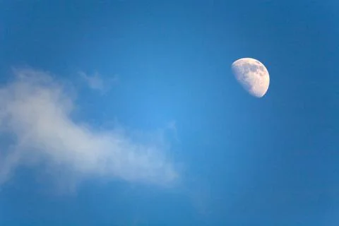 Half moon and a small cloud in the blue sky. Stock Photos