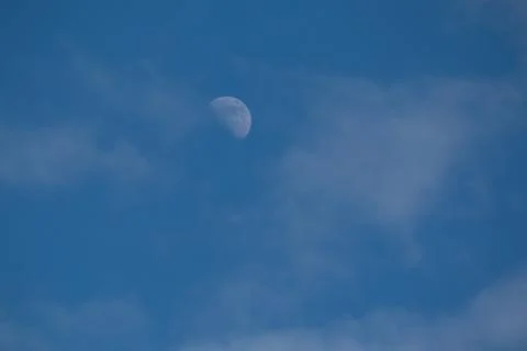 A half-moon and thin clouds on a blue sky Stock Photos