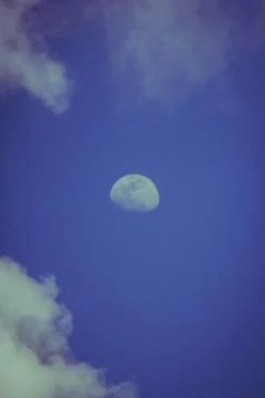 Half moon in the blue sky with some clouds in the evening Stock Photos