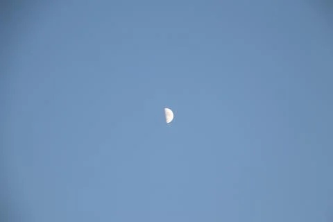 Half moon during day time on a blue sky. Copy space. Stock Photos