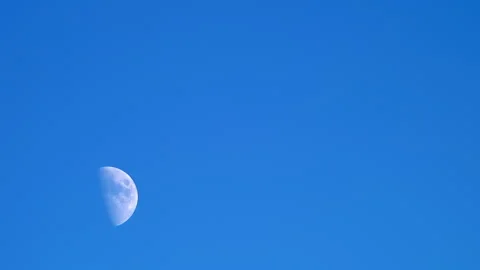 A half moon moving across a blue sky, half moon at twilight. Stock Footage 253821465