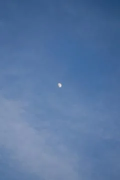 Half the moon is trying to hide behind the clouds. Stock Photos