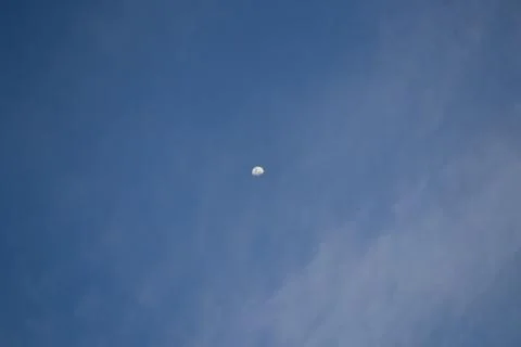 Half the moon is trying to hide behind the clouds. Stock Photos