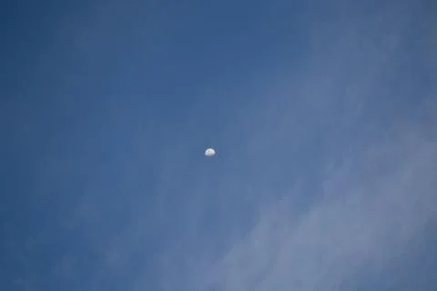 Half the moon is trying to hide behind the clouds. Stock Photos