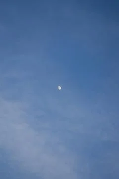 Half the moon is trying to hide behind the clouds. Stock Photos