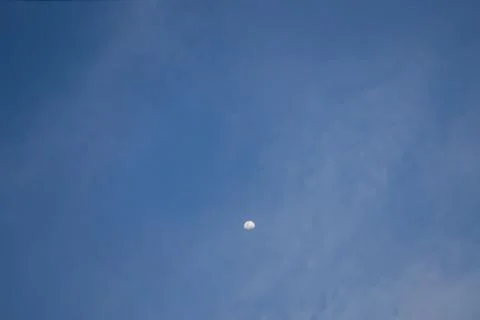 Half the moon is trying to hide behind the clouds. Stock Photos