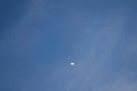 Half the moon is trying to hide behind the clouds. Stock Photos