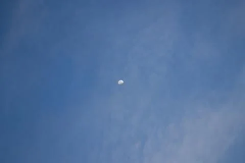 Half the moon is trying to hide behind the clouds. Stock Photos