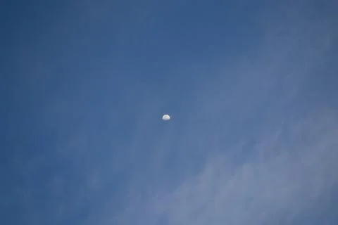 Half the moon is trying to hide behind the clouds. Stock Photos