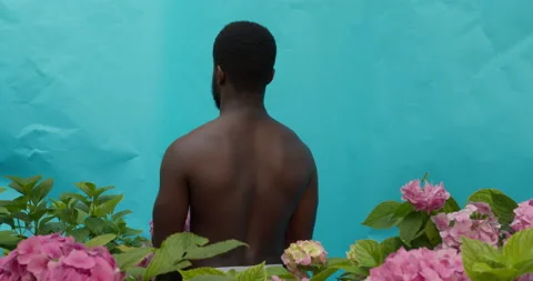 A half-naked dark-skinned man with a serious expression offers you a bouquet of Video stock 159511260