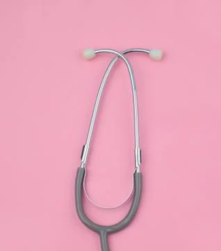 Half of one single normal stethoscope isolated on top of a pink color paper b Stock Photos