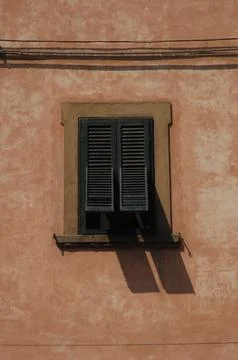 Half-Open Green Shutter on a Sunlit Ochre Wall Foto stock