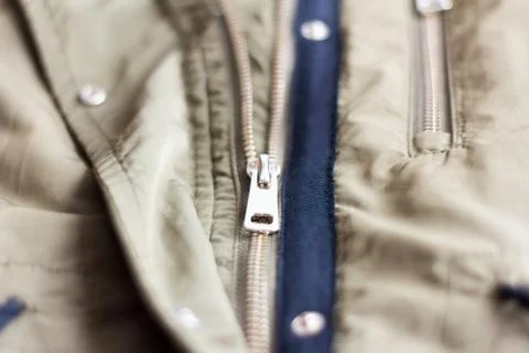 A half-open metal lock on a light khaki jacket. Stock Photos