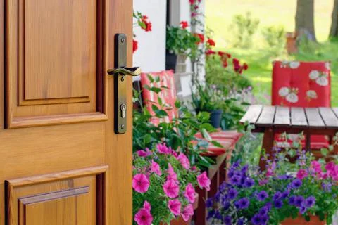 Half opened door into the beautiful summer terrace and  blooming garden Stock Photos