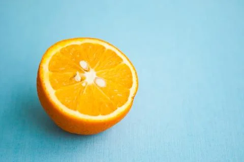 Half of orange on blue background with copy space Stock Photos