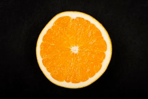 Half of an orange on dark background Stock Photos