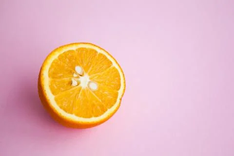 Half of orange on pink background with copy space Stock Photos