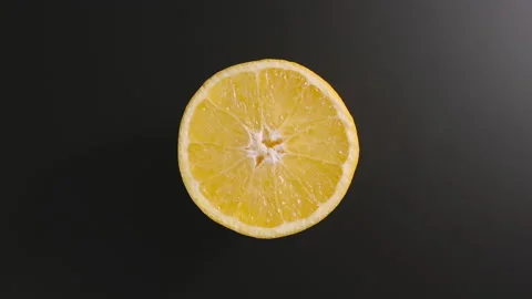 Half of an orange rotates on a black surface. Top view. Stop motion Stock Footage 131588481