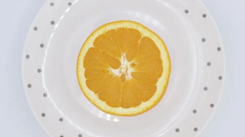 Half orange seen from above, rotating on a plate with grey dots Stock Footage 145813681