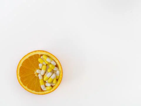 Half an orange with vitamins inside. Oranges and capsules with vitamins on a Stock Photos