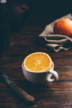 Half of orange in a white cup Stock Photos