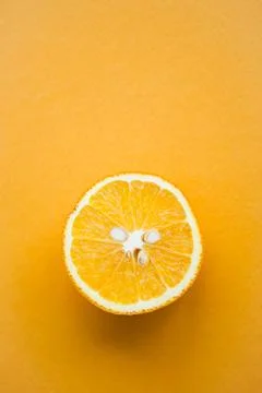 Half of orange on yellow background with copy space Stock Photos