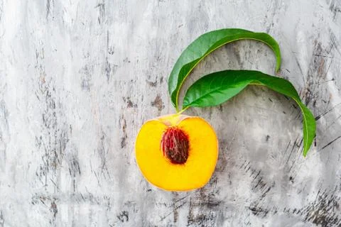 Half peach with leaf on gray concrete background. Fresh sweet peach with pitt Stock Photos