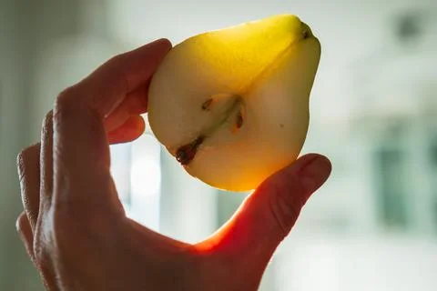 Half pear glowing in warm sunlight revealing translucent fruit texture Stockfoto's