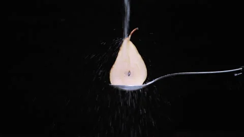 Half pear with tail pour slow sugar jet on black background Stock Footage 131406313