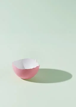Half of a pink eggshell on a green background with a shadow of the whole eg.. Stock Photos