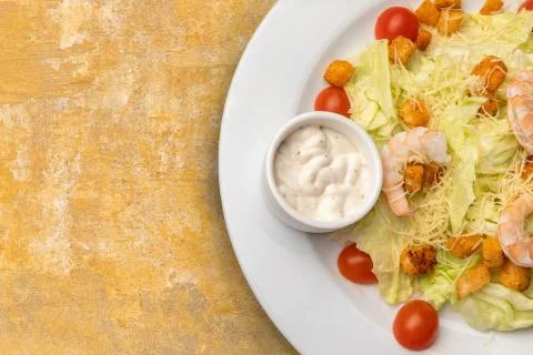Half a plate of Caesar salad on textured table Stock Photos