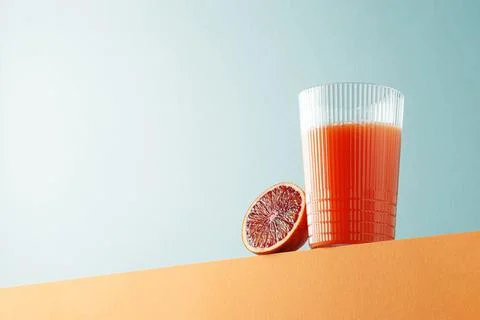 Half raw organic red orange and a glass of orange juice on yellow surface Stock Photos