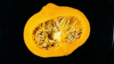 Half of raw pumpkin with seeds isolated on black background. Rotation in 4K Vídeo Stock 74060309