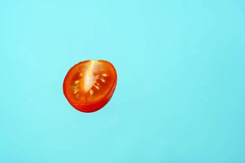 Half a red tomato with drops on a blue background Stock Photos
