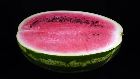 Half of red watermelon, rotating on black background against the clock close up Stock Footage 84074279