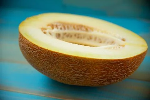 Half ripe melon on a rustic, blue wooden background Stock Photos