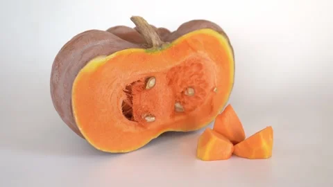 Half of a ripe orange pumpkin next to diced pumpkin pulp on a white background. Stock Footage 254712878