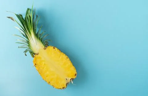 Half ripe pineapple on blue background. Stock Photos
