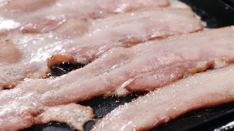 Half roasted bacon pieces on a frying pan Stockbeeldmateriaal 102606797