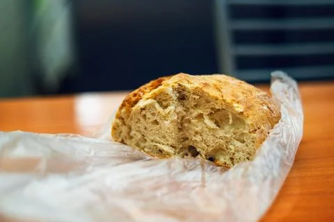 Half a round rustic bread loaf in plastic bag on table with several slices .. Stock Photos