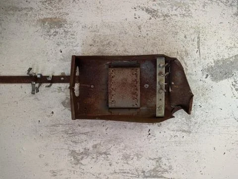 Half of a rusty metal box from a meter that hangs on an old white wall of a r Foto stock