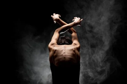 Half silhouette modern ballet dancer posing on dark background with smoke Stock Photos
