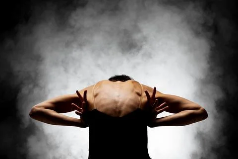 Half silhouette modern ballet dancer posing on dark background with smoke Stock Photos