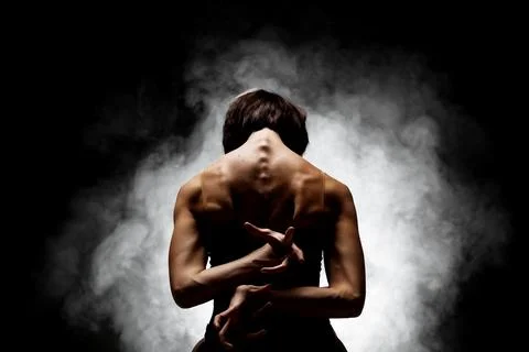 Half silhouette modern ballet dancer posing on dark background with smoke Stock Photos