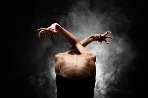 Half silhouette modern ballet dancer posing on dark background with smoke Stock Photos