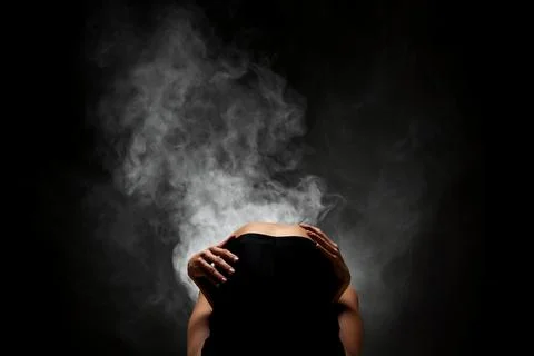 Half silhouette modern ballet dancer posing on dark background with smoke Stock Photos