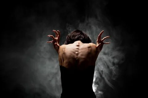 Half silhouette modern ballet dancer posing on dark background with smoke Stock Photos