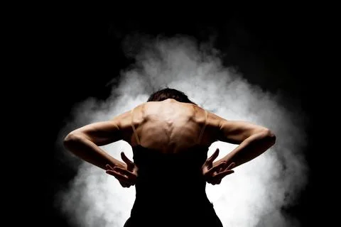 Half silhouette modern ballet dancer posing on dark background with smoke Stock Photos