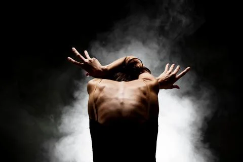 Half silhouette modern ballet dancer posing on dark background with smoke Stock Photos